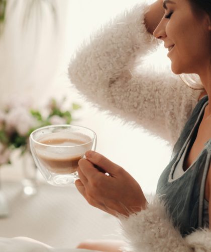 a relaxed girl at home drinks coffee and watches a movie.Domestic calm.The girl is sitting comfortably on the sofa and drinking coffee.